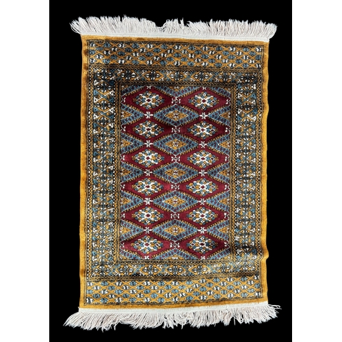 6 - Rugs: a 20th C Bokhara rug, deep red diamonds within a light brown and blue border, approximately 14... 