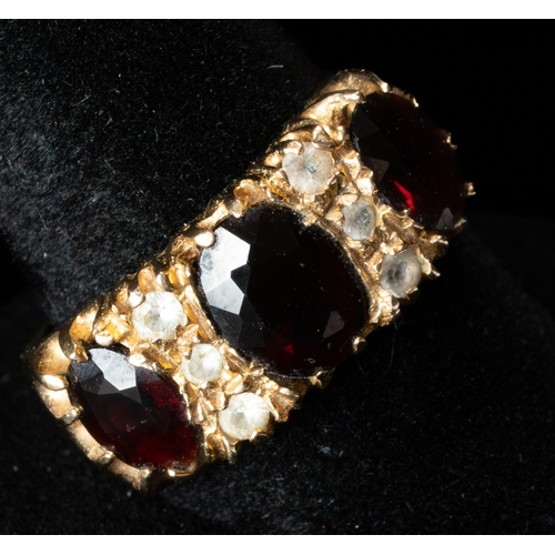 496 - Jewellery: a 9ct gold ring set with three garnets, divded by rows of three white stones. UK size Q, ... 