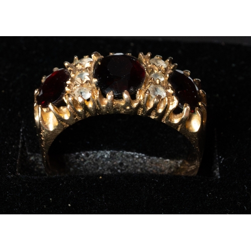 496 - Jewellery: a 9ct gold ring set with three garnets, divded by rows of three white stones. UK size Q, ... 