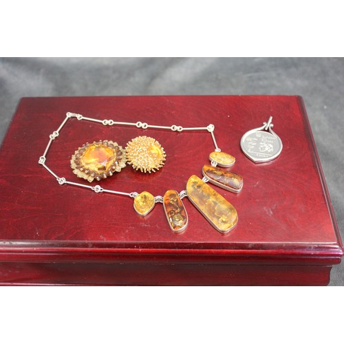 29 - A silver and amber necklace, two costume brooches, and a 1976 Montreal Olympics pendant, all in maho... 