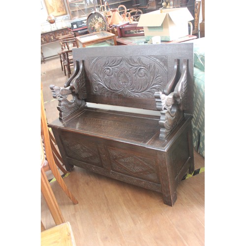 270 - An early 20th century dark stained wood and carved oak monks bench, with rising top, 106cm wide.