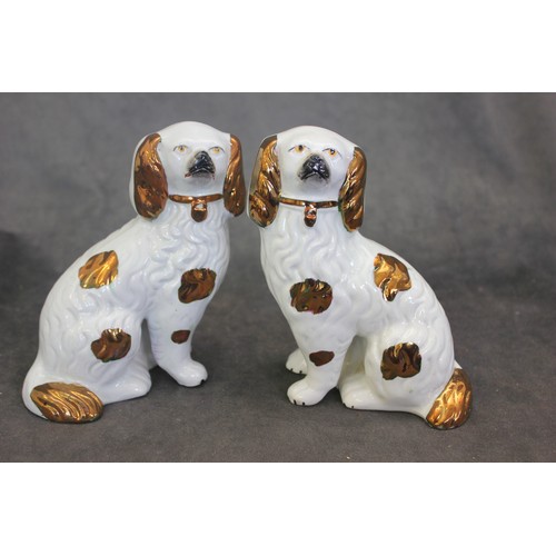 56 - A matched pair of Staffordshire spaniel figures, some copper lustre decoration, each 15cm high.