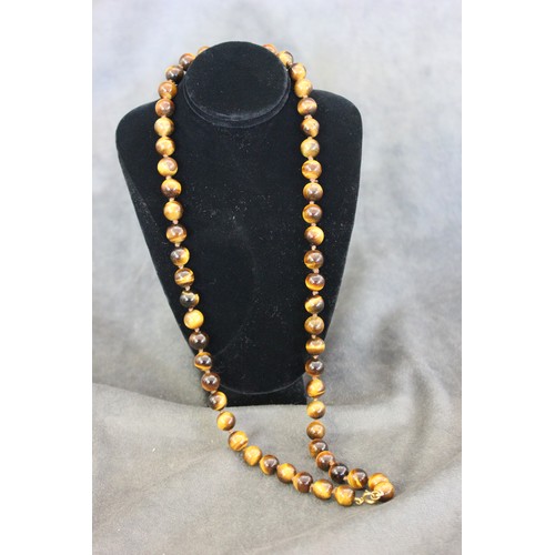 265 - A tiger's eye bead necklace, of fifty-five beads, with base metal clasp, 62cm long.