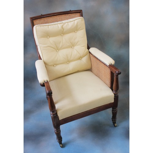 81 - A Regency mahogany bergere chair, with caned rectangular back and side panels, padded arms, with dis... 