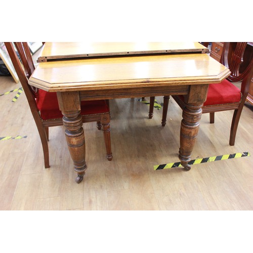 2 - A Victorian oak wind-out dining table, with canted corners, on turned and ringed legs, and castors, ... 