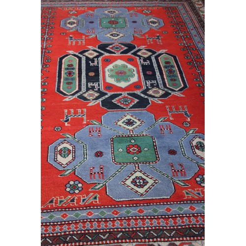 5 - A Caucasian rug, the central field with three large medallions, in black, greens, orange, and white,... 