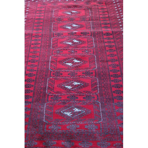 6 - A Bokhara rug, the centre with six rectangular medallions, on red ground, decorative inner and outer... 