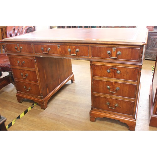 254 - A reproduction walnut pedestal desk, fitted nine drawers, the pedestal on bracket feet, 136cm wide.