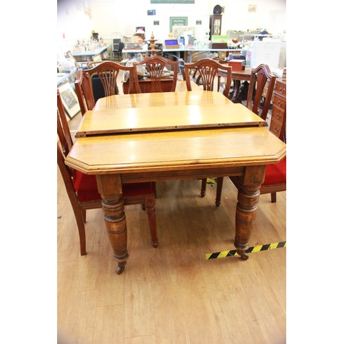 256 - A Victorian oak wind-out dining table, with canted corners, on turned and ringed legs, and castors, ... 