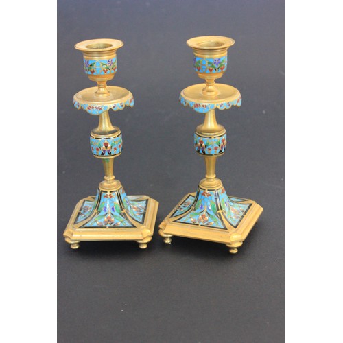 26 - A pair of gilt brass and enamelled candlesticks on square form bases each 18cm high.