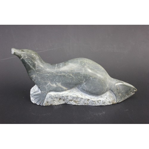 41 - An Inuit soapstone carved figure of a seal, on landscaped base, 48cm long.