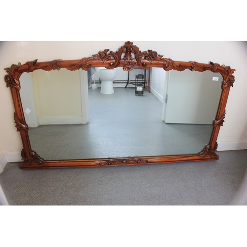 274 - An overmantle mirror in decoration carved wood frame, 92cm high x 142cm wide.