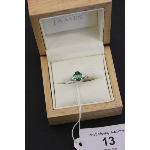 13 - An 18ct white gold dress ring, set a green tourmaline, and two small diamonds.