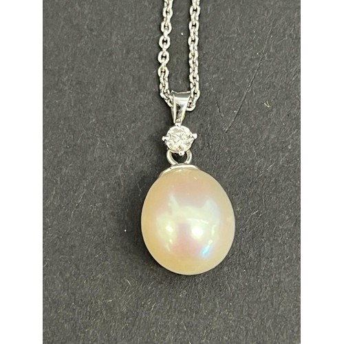 9 - An 18ct white gold diamond and pearl pendant, on slender link chain.