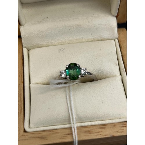 13 - An 18ct white gold dress ring, set a green tourmaline, and two small diamonds.