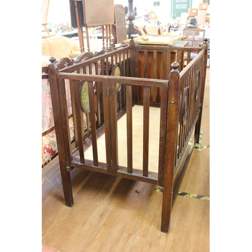 43 - An Edwardian oak collapsible cot, the slatted sides with oval transfer panels of 