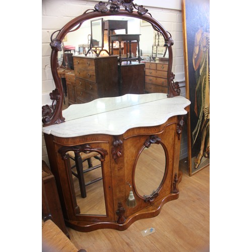 64 - A Victorian walnut credenza with marble top & mirrored back, above three mirrored panel doors, 135cm... 