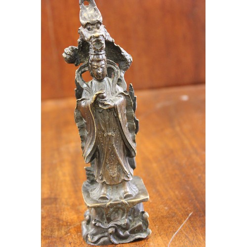 44 - A 20th century Chinese bronze figure of Guanyin, standing below a dragon, 21cm high.