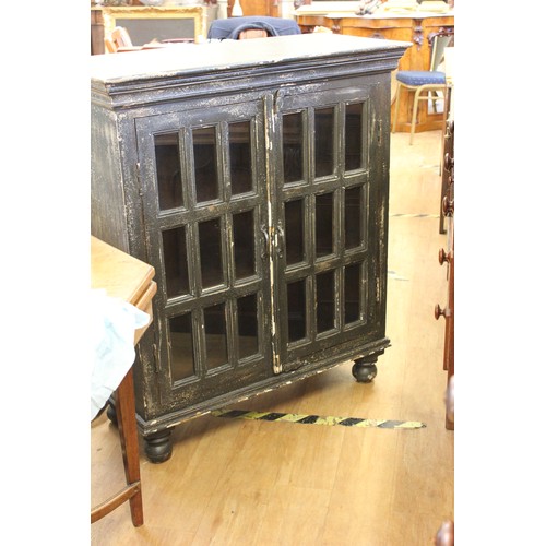 221 - A stained and painted wooden bookcase with glazed and panelled doors on bun feet, 97cm wide.