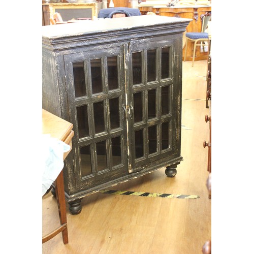 221 - A stained and painted wooden bookcase with glazed and panelled doors on bun feet, 97cm wide.