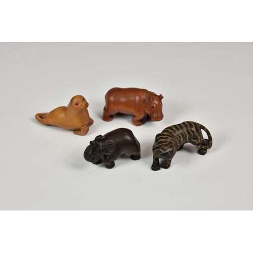 913 - A group of four 20th century carved Japanese netsuke, comprising a tiger, elephant, sea lion and hip... 