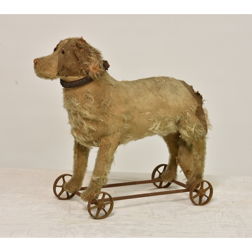 351A - A late 19th to early 20th century dog pull along toy, stuffed mohair on iron frame and wheels, origi... 