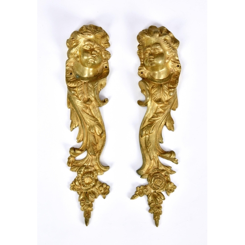 2864 - A pair of ormolu furniture mounts, cast with cherub face masks and floral and foliate design, 10 ¾in... 