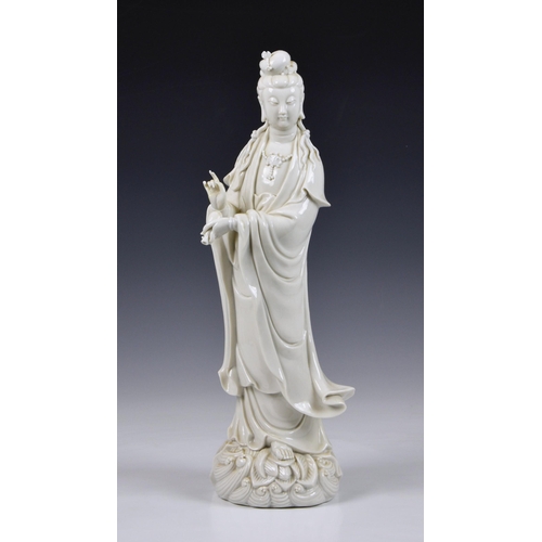 68 - A Blanc de Chine figure of Guanyin, Continental, 20th century, figure holding a vase, standing on lo... 