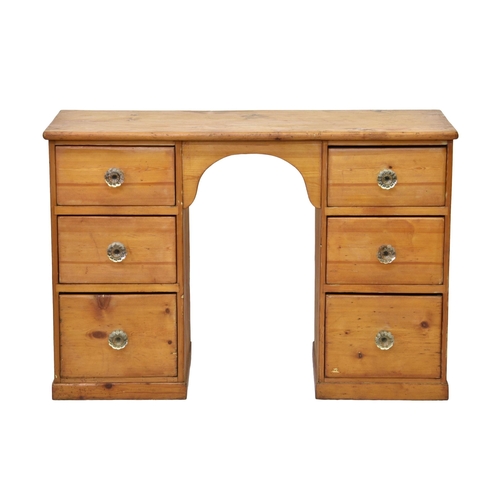 775 - An early 20th century pine kneehole desk, the arched kneehole flanked by two banks of three drawers ... 