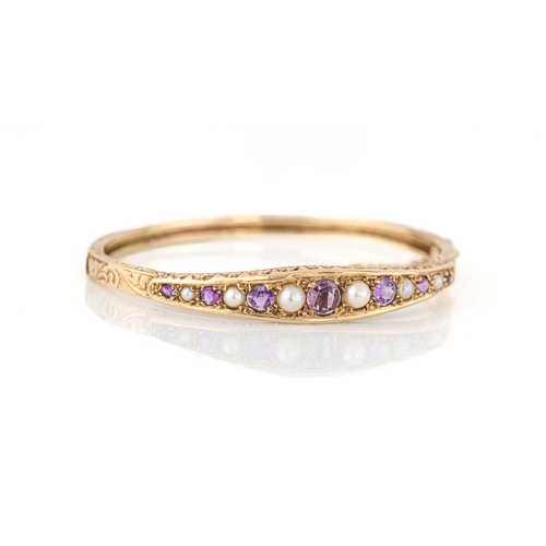 1165 - A Victorian style 9ct gold, amethyst and pearl bangle, set with seven graduated round cut amethysts ... 