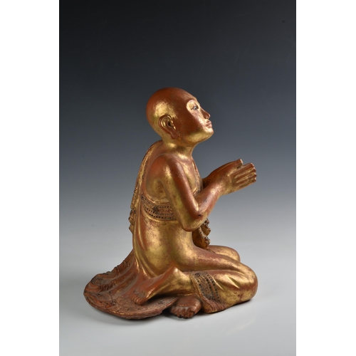 1622 - A Burmese Mandalay carved and jewelled gilt wood figure of a seated monk, probably late 19th century... 