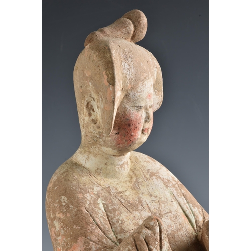 1623 - A Chinese Tang Dynasty (AD 618-906) pottery figure of a Court Lady, modelled standing with her body ... 