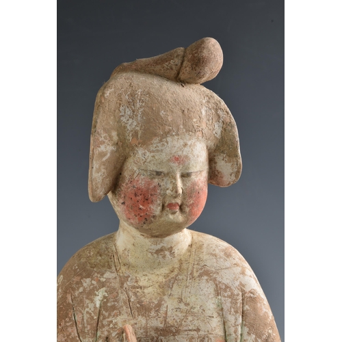 1623 - A Chinese Tang Dynasty (AD 618-906) pottery figure of a Court Lady, modelled standing with her body ... 