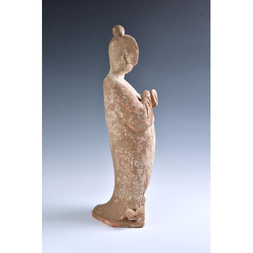 1623 - A Chinese Tang Dynasty (AD 618-906) pottery figure of a Court Lady, modelled standing with her body ... 