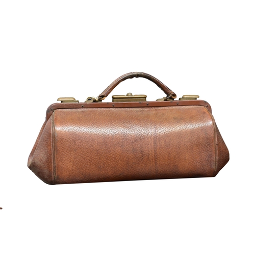 1982 - An antique dark tan leather suitcase, the heavy leather case with brass fittings, the interior with ... 