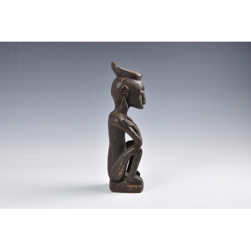 2094 - Tribal art - A carved wooden ancestor figure, Indonesia, probably Leti Islands, seated with arms cro... 