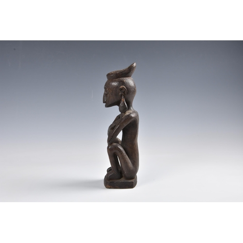 2094 - Tribal art - A carved wooden ancestor figure, Indonesia, probably Leti Islands, seated with arms cro... 