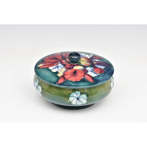 5 - A Moorcroft Pottery powder bowl and cover, 'Frilled and Slipper Orchid' pattern, on a shaded blue-gr... 