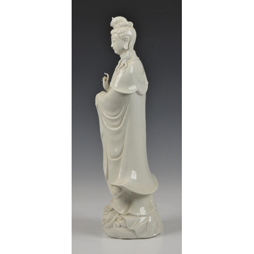 66 - A Blanc de Chine figure of Guanyin, Continental, 20th century, figure holding a vase, standing on lo... 