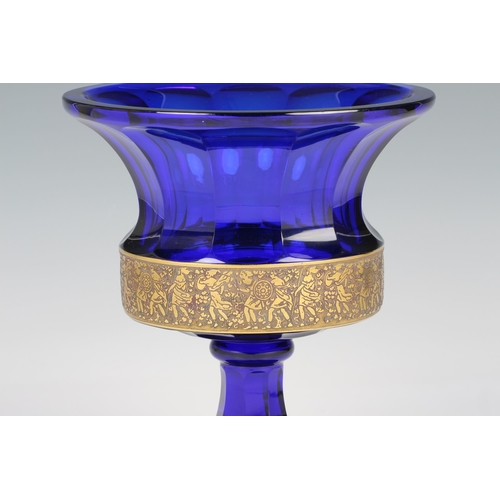 91 - A Moser cobalt blue glass urn with flared rim, acid cut neo classical gilt freeze encircling the bas... 