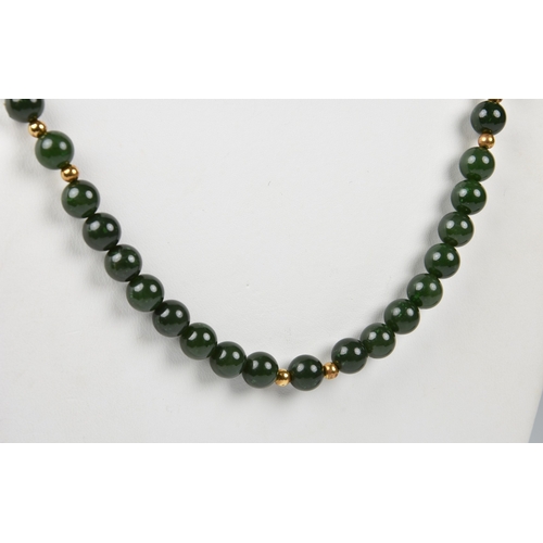 1260 - A dark spinach jade bead and 18ct gold necklace, the evenly sized 7mm. jade beads interspersed with ... 