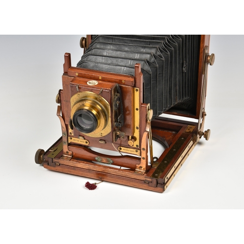 2085 - A Thornton Pickard mahogany cased field camera with tripod, brass fittings and lens, having ivorine ... 