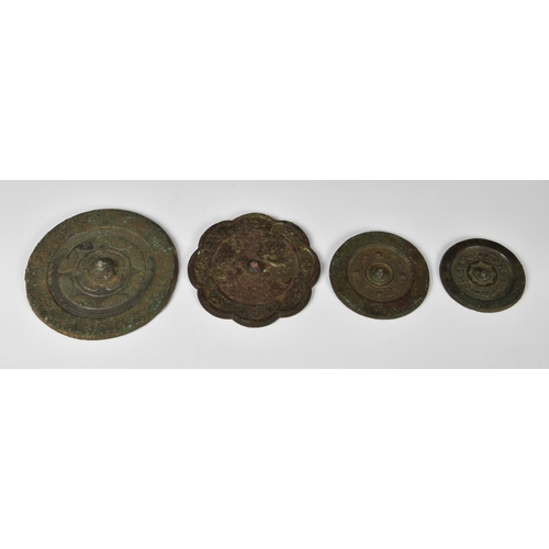 1240 - Four Chinese bronze mirrors, probably Sui or Tang Dynasty, to include three of circular shield form,... 