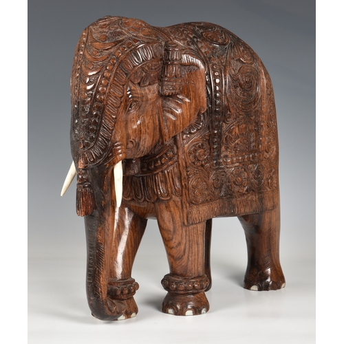 1258 - A large Indian carved hardwood figure of a caparisoned elephant, mid-20th century, 15in. (38cm.) hig... 