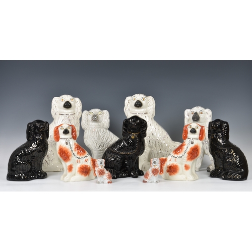 29 - A collection of Staffordshire seated dogs, to include a white version with traditional embellishment... 