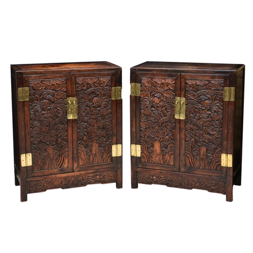 1245 - A pair of Chinese carved hardwood cabinets, the plain rectangular top over two cupboard doors with a... 