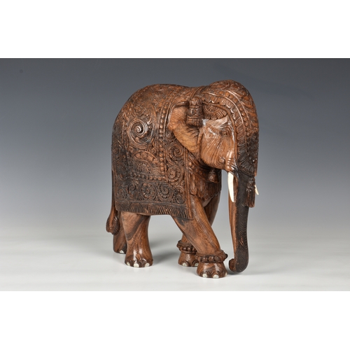 1258 - A large Indian carved hardwood figure of a caparisoned elephant, mid-20th century, 15in. (38cm.) hig... 