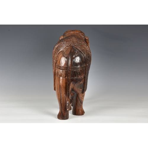 1258 - A large Indian carved hardwood figure of a caparisoned elephant, mid-20th century, 15in. (38cm.) hig... 