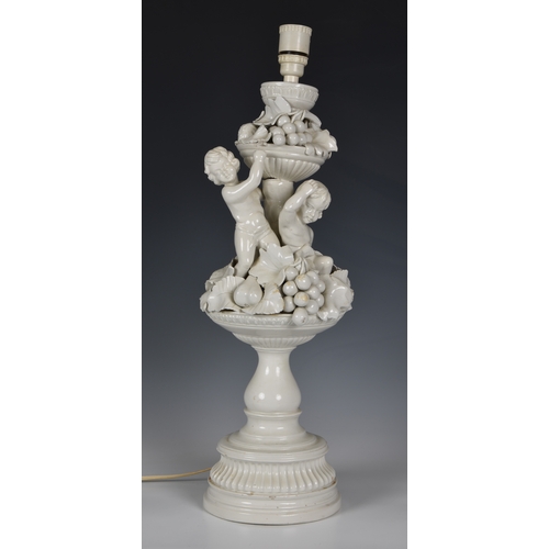 45 - An Italian white glazed pottery table lamp, mid-20th century, modelled as two cherubs seated on an u... 