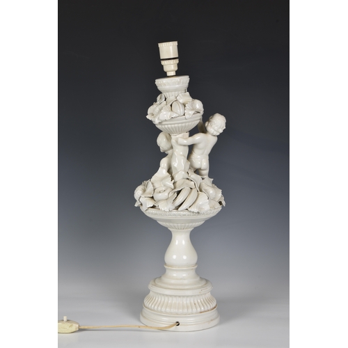 45 - An Italian white glazed pottery table lamp, mid-20th century, modelled as two cherubs seated on an u... 